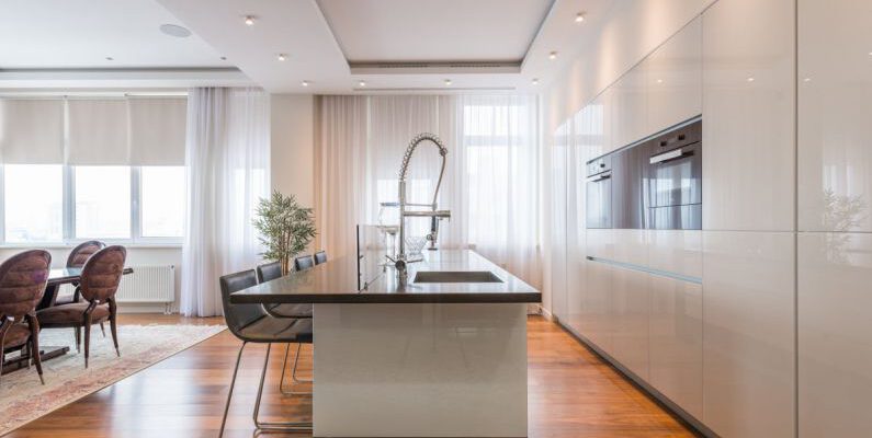 Island Estates - Interior of spacious kitchen with modern minimalist furniture with built in appliances and dining zone in contemporary apartment in daylight