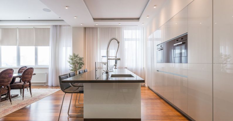 Island Estates - Interior of spacious kitchen with modern minimalist furniture with built in appliances and dining zone in contemporary apartment in daylight